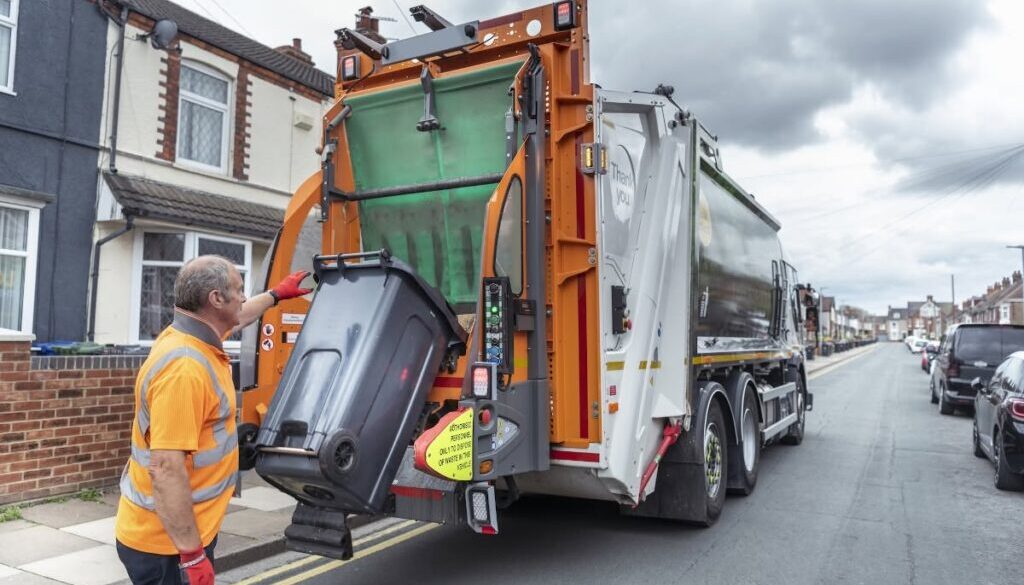 Refuse collector and refuse truck in street