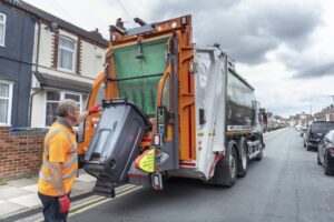 Refuse collector and refuse truck in street