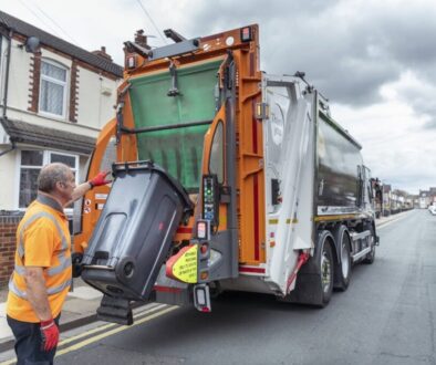 Refuse collector and refuse truck in street